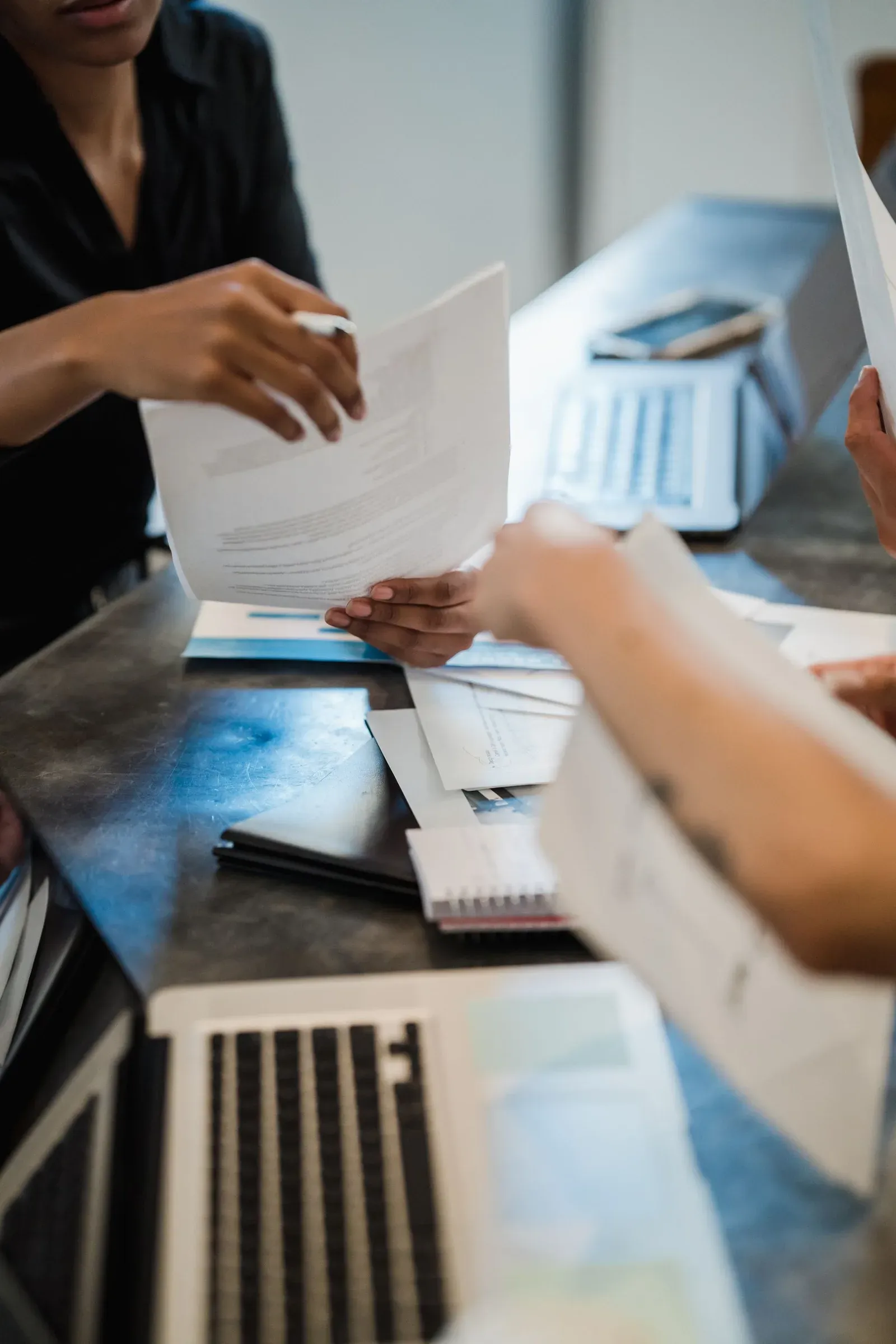 Profesionales revisando documentos junto a una laptop
